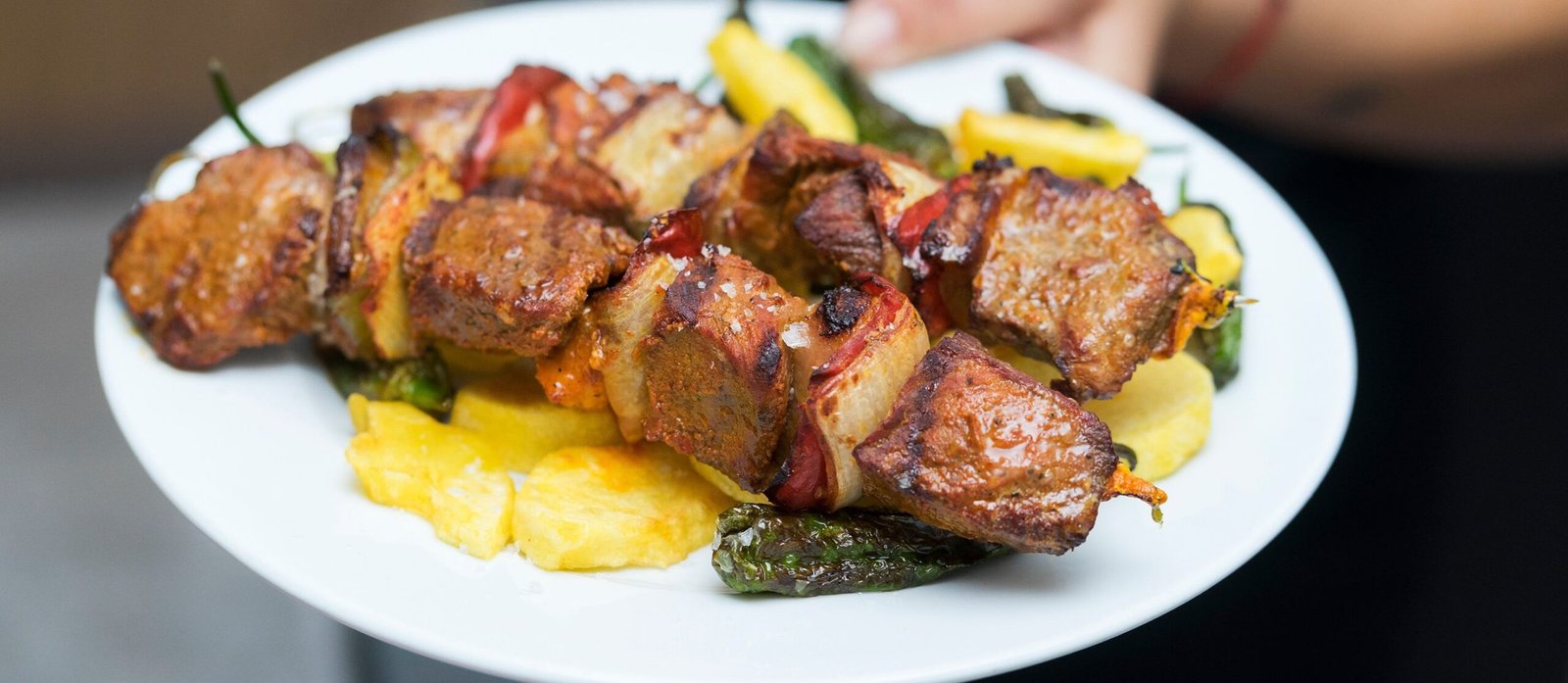 Goat brochette grilling over charcoal with peppers and potatoes in Rwanda